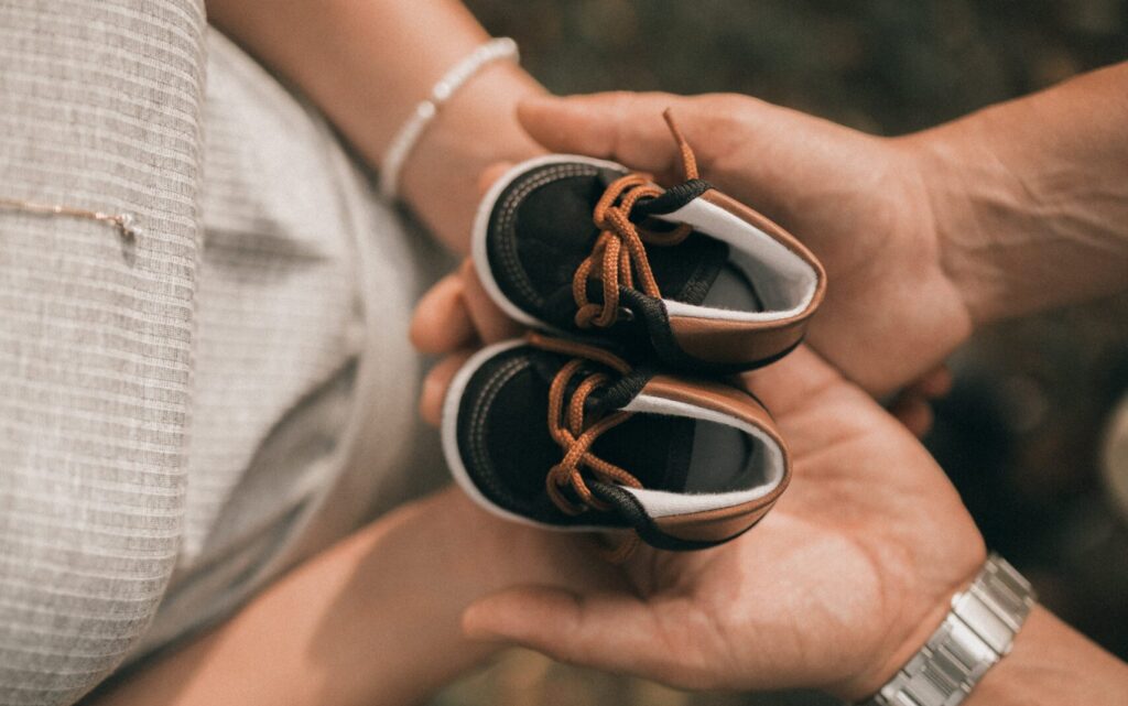 https://www.pexels.com/photo/couple-holding-together-adorable-baby-shoes-19471466/
